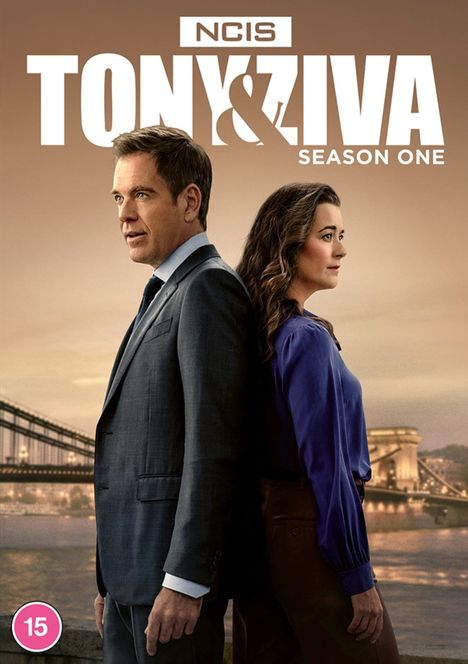 "NCIS: Tony & Ziva, Season One". Zwei Personen stehen Rücken an Rücken, ein Mann im Anzug und eine Frau in Bluse.