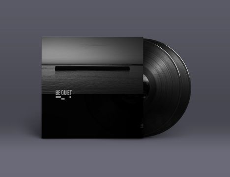 Schwarze Vinyl-Schallplatte und Hülle mit dem Schriftzug "BE QUIET" über einem ruhigen, grauen See bei Sonnenaufgang.