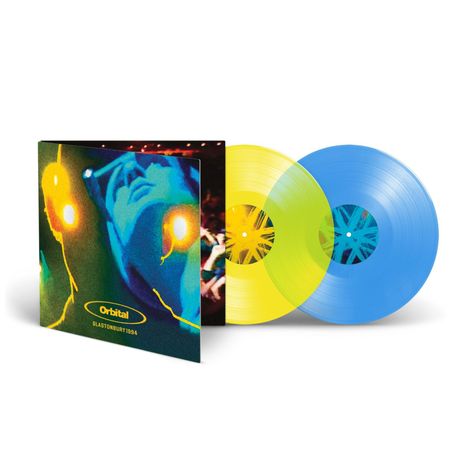 Text: "Orbital GLASTONBURY 1994". Zwei farbige Vinyl-Schallplatten, eine gelb, eine blau, und ein Albumcover mit abstraktem Gesichtsmotiv.