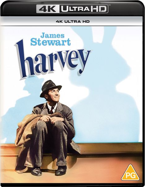 James Stewart; harvey. Ein Mann in Anzug und Hut sitzt lächelnd neben einem Schatten in Hasenform.