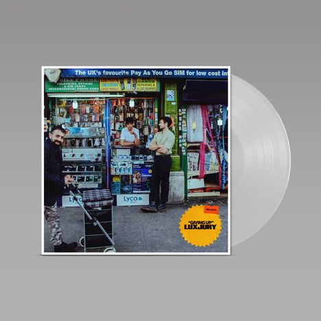 "UK's favourite Pay As You Go SIM" und "GIVING UP LUXURY". Zwei Personen stehen vor einem Handyshop. Ein Mann mit Trolley.