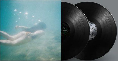 Keine Texte im Bild. Eine unter Wasser schwimmende Person neben zwei schwarzen Vinyl-Schallplatten.