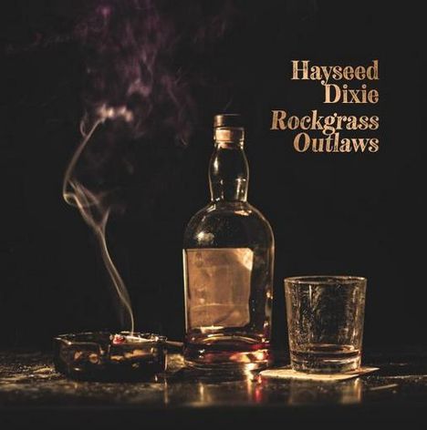 Text: "Hayseed Dixie Rockgrass Outlaws". Eine Flasche, ein Glas und ein Aschenbecher mit brennender Zigarette.