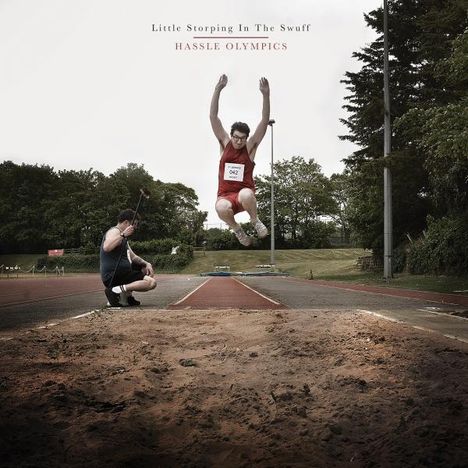 "Little Storping In The Swuff. HASSLE OLYMPICS." Ein Sportler springt in eine Sandgrube, ein Fotograf kniet daneben.