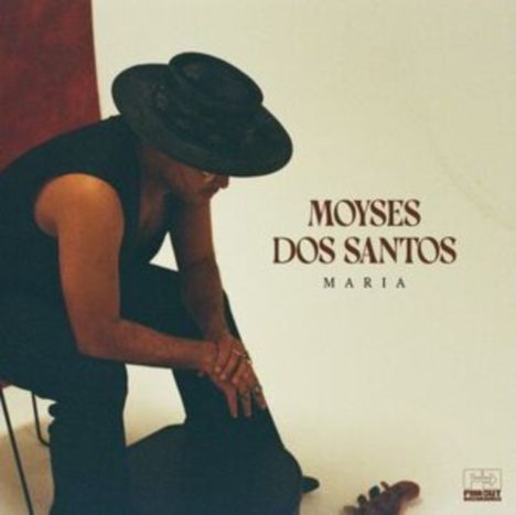 Text: "MOYSES DOS SANTOS MARIA". Eine Person sitzt seitlich, trägt einen schwarzen Hut und dunkle Kleidung.