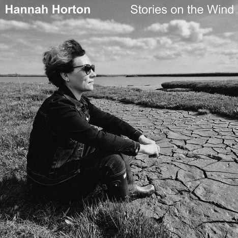 Oben steht "Hannah Horton", "Stories on the Wind". Eine Person sitzt draußen auf trockenem Boden, blickt in die Ferne.