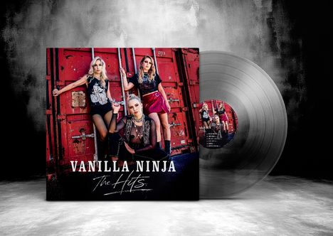 "Vanilla Ninja The Hits" steht auf einem Albumcover. Drei Frauen posieren vor roten Containertüren. Eine Schallplatte ist daneben.