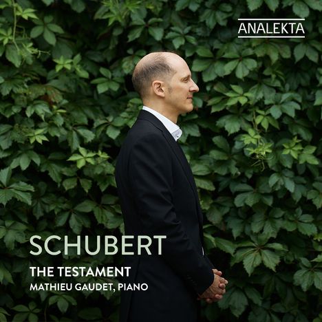 ANALAKTA, SCHUBERT, THE TESTAMENT, MATHIEU GAUDET, PIANO. Ein Mann im Anzug vor einer grünen Blätterwand im Profil.