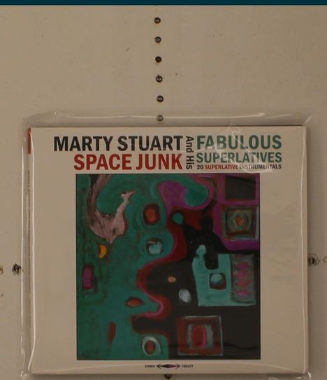 "SPACE JUNK" in roter und "FABULOUS SUPERLATIVES" in grüner Schrift, darunter abstrakte Kunst in kräftigen Farben.