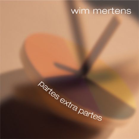 Oben steht "wim mertens", unten "partes extra partes". Unscharfes, rotierendes, mehrfarbiges Objekt in der Mitte.
