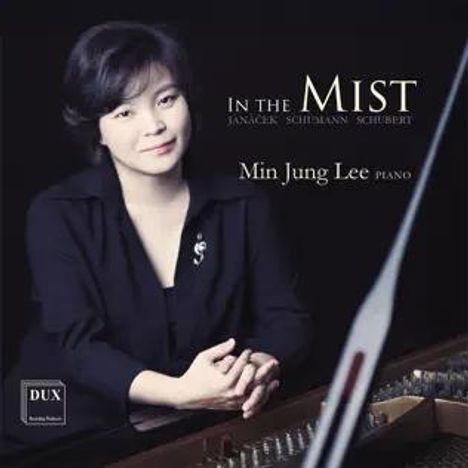 „In the Mist. Janáček Schumann Schubert. Min Jung Lee Piano.“ Eine Frau in schwarzer Kleidung sitzt an einem Klavier.