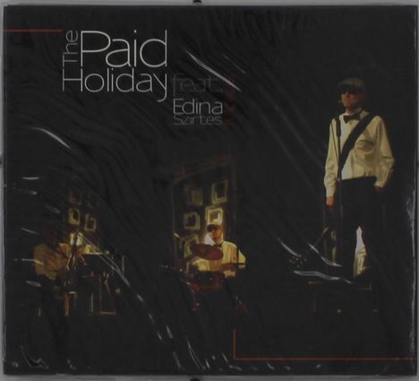 "The Paid Holiday feat. Edina Szirtes." Dunkle Bühne mit Musikern: Schlagzeuger und Sänger in weißen Hemden.