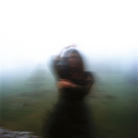 Ein verschwommenes Bild einer Person in Nebel, die sich bewegt. Die Umgebung ist unscharf und düster.