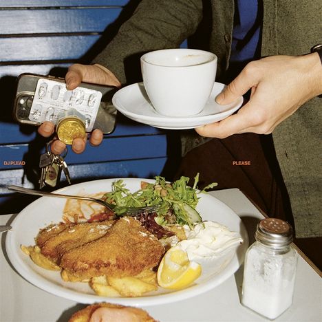 DJ PLEAD, PLEASE. Eine Hand hält eine Kaffeetasse, daneben ein Teller mit Schnitzel, Pommes und Salat.