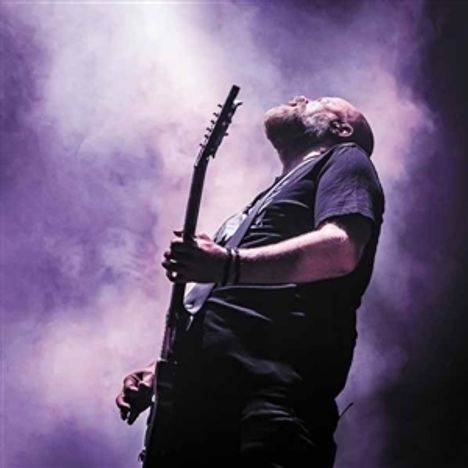 Ein Mann spielt Gitarre in einer dramatischen Pose, umgeben von dichtem, lila beleuchtetem Nebel.