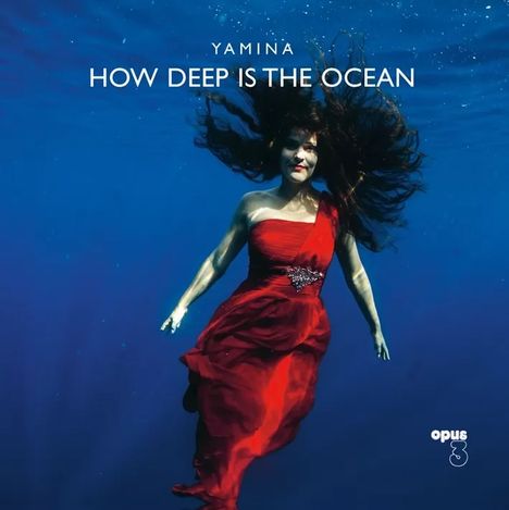 Text: "YAMINA HOW DEEP IS THE OCEAN"  
Eine Frau in einem roten Kleid schwimmt unter Wasser.