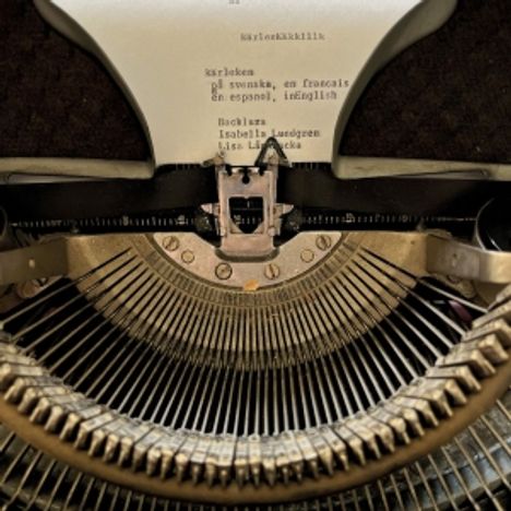 „kärleken på svenska...“ ist auf Papier einer mechanischen Schreibmaschine getippt. Tastatur und Typenhebel sind sichtbar.
