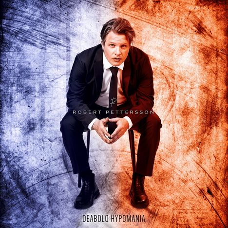 ROBERET PETTERSSON, DEABOLO HYPOMANIA. Ein Mann im Anzug sitzt vor einem zweifarbigen Hintergrund, links blau, rechts rot.