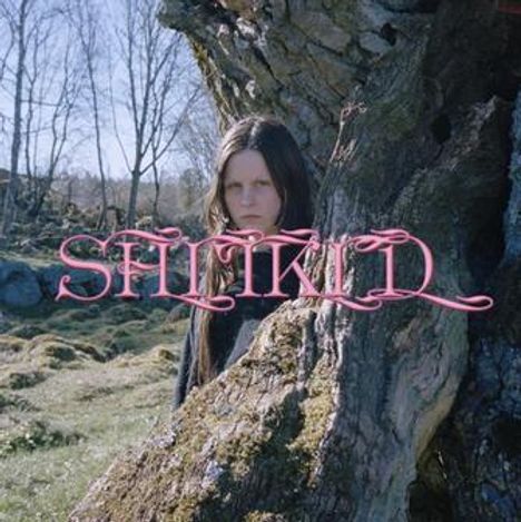 „SUFIKID“ in rosa Schrift zentriert. Ein Mensch steht teilweise verdeckt hinter einem Baumstamm in einer bewaldeten Landschaft.