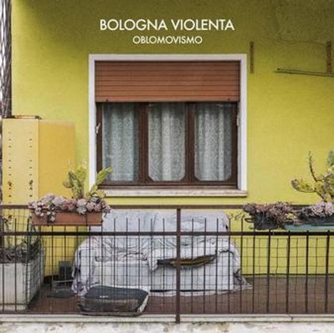 "Bologna Violenta Oblomovismo" steht oben. Darunter ein gelber Hausanstrich und ein Balkon voller Pflanzen.