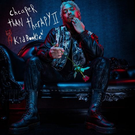 "Cheaper Than Therapy II, Kid Bookie." Ein Mann sitzt auf einem Ledersofa, trägt eine Jacke mit Muster und hält eine Rose.