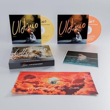"Ultimo" auf zwei CD-Hüllen, eine gelb, eine orange. Darunter eine Box und ein Foto. Ein farbiges Poster zeigt Wolken.