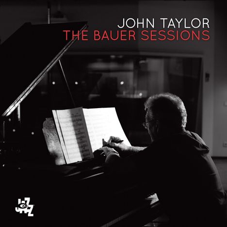 JOHN TAYLOR, THE BAUER SESSIONS. Ein Mann spielt Klavier und studiert Notenblätter. Schwarz-weiß, ruhige Atmosphäre.