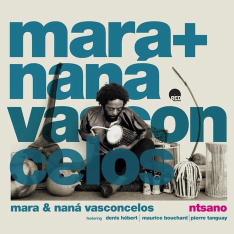 "Mara + Nana Vasconcelos" in großen Buchstaben. Ein Mann spielt ein Perkussionsinstrument, umgeben von traditionellen Instrumenten.