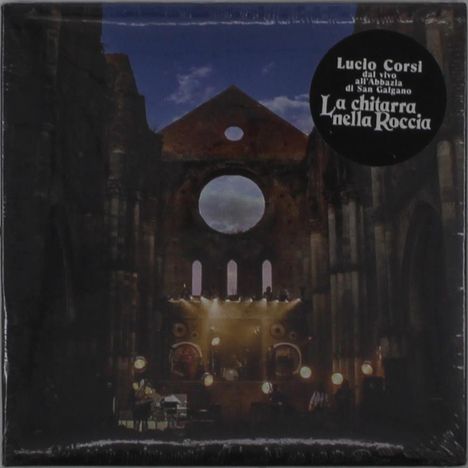 Text: "Lucio Corsi dal vivo all'Abbazia di San Galgano La chitarra nella Roccia." Dunkle Kirche mit Lichteffekten.