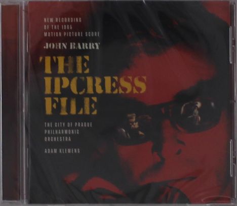 Text: "New Recording of the 1965 Motion Picture Score John Barry The Ipcress File The City of Prague Philharmonic Orchestra Adam Klemens." Im Hintergrund ein stilisierter Gesichtsausschnitt mit Brille.
