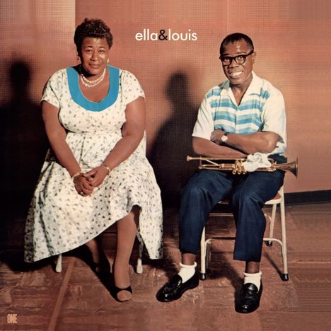 Text: "ella&louis". Zwei Personen sitzen nebeneinander, die linke in einem Kleid, die rechte mit Hemd und einer Trompete.