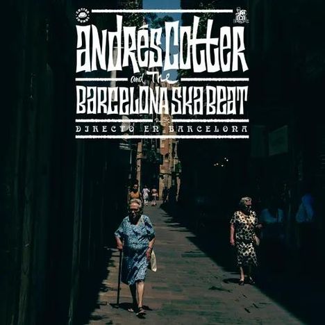"Andres Cotter and The Barcelona Ska Beat, Directo en Barcelona." Drei Frauen gehen durch eine schattige, enge Straße.