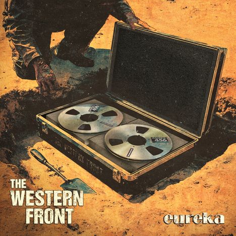 Text: "THE WESTERN FRONT" und "eureka". Illustration: Koffer mit Tonbandspulen im Boden vergraben, daneben eine Schaufel.