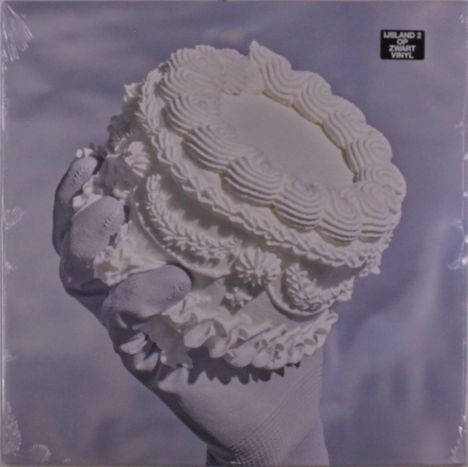 Text: "ISLAND 2 OP ZWART VINYL". Eine weiße, kunstvoll dekorierte Torte wird von einer behandschuhten Hand gehalten.