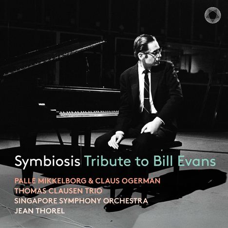 "Symbiosis Tribute to Bill Evans" steht über einem sitzenden Mann im Anzug neben einem Flügel.
