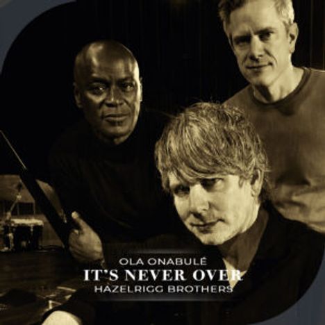 Text: "Ola Onabulé, It's Never Over, Hazelrigg Brothers." Drei Männer in einem dunklen Raum, warm beleuchtet.