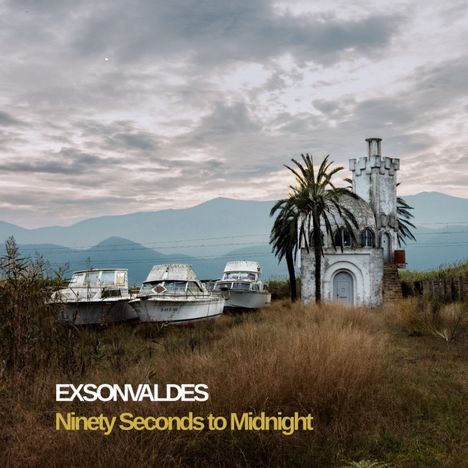 EXSONVALDES, Ninety Seconds to Midnight. Boote vor einem kleinen, weißen Turm und Palmen, Berge im Hintergrund.