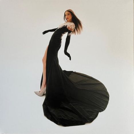 Keine sichtbaren Texte. Eine Person in einem langen, schwarzen Kleid mit weißen Details und hochgeschlitztem Rock.