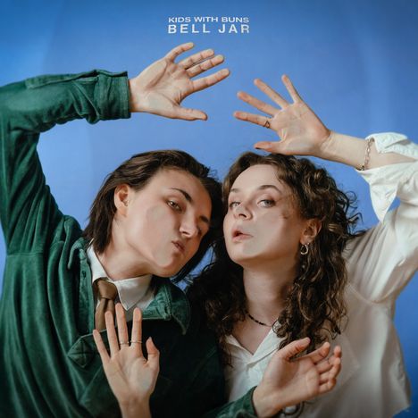 Text: "KIDS WITH BUNS BELL JAR". Zwei Personen in interessanter Pose vor blauem Hintergrund.