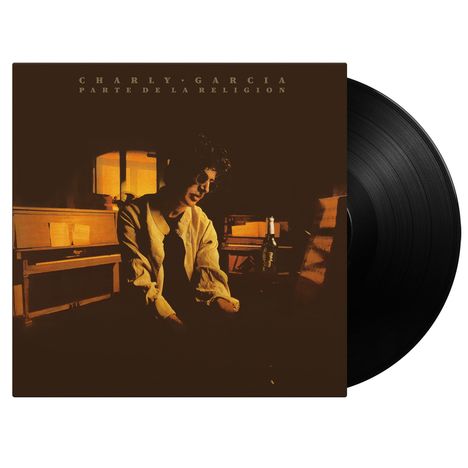 "CHARLY GARCÍA PARTE DE LA RELIGIÓN". Ein Mann sitzt nachdenklich an einem Piano, beleuchtet von warmem Licht.