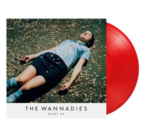 "The Wannadies, Bagsy Me." Eine Person in blauer Bluse und Rock liegt auf herbstlichem Boden. Rote Vinyl-Schallplatte.