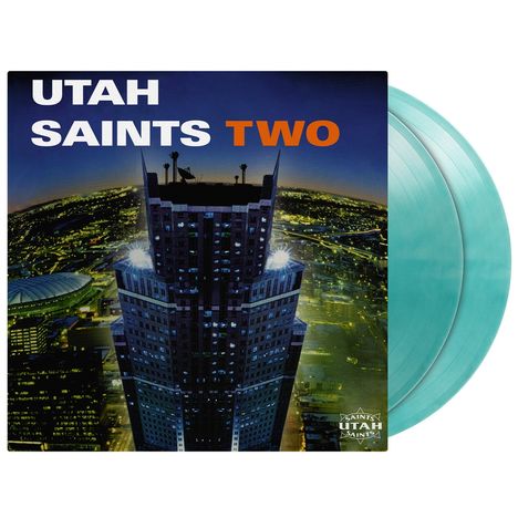 Text: "UTAH SAINTS TWO". Darstellung: Nachtansicht eines beleuchteten Wolkenkratzers mit Blick auf eine Stadt.