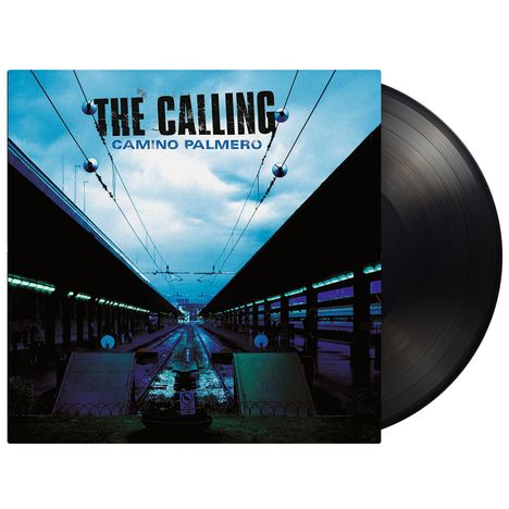 "THE CALLING, CAMINO PALMERO". Dunkles Bahngleis mit leuchtenden Lichtern und bewölktem Himmel.