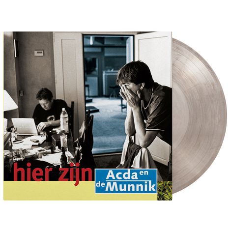 Text: "hier zijn Acda en de Munnik." Zwei Männer in einem Raum, einer sitzt am Tisch, der andere steht mit Händen am Gesicht. Vinylalbum daneben.
