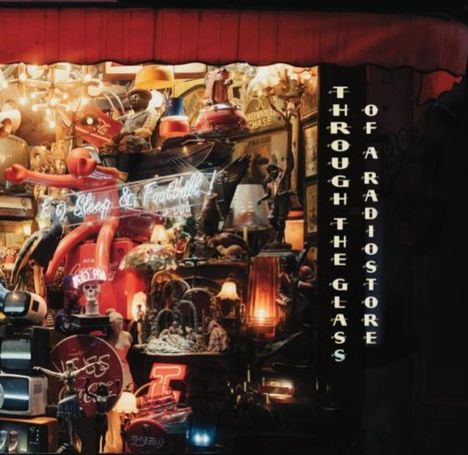 Text: "THROUGH THE GLASS OF A RADIOSTORE." Ein Schaufenster voller Retro-Radios und Leuchten, dekorativ angeordnet.