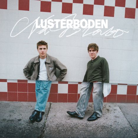 "LUSTERBODEN" in Weiß oben. Zwei junge Männer lehnen an einer gefliesten Wand mit roten und weißen Kacheln.