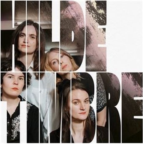 Text "HILDE TIMBRE" in großen Buchstaben. Dahinter sind vier Personen sichtbar.