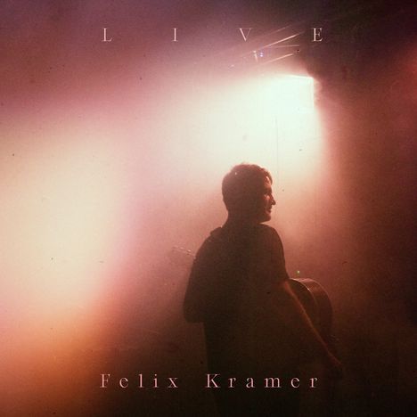 Text: "LIVE Felix Kramer". Ein Musiker steht im diffusen Licht und hält eine Gitarre, umgeben von warmen Farbtönen.