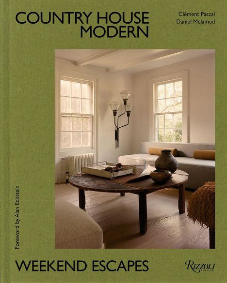 "COUNTRY HOUSE MODERN", "WEEKEND ESCAPES". Helles Wohnzimmer mit Sofa, rundem Holztisch und Keramikvasen.