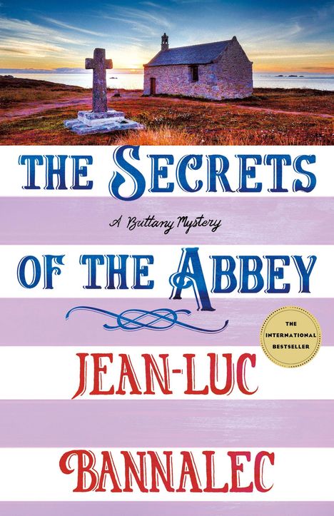 "The Secrets of the Abbey" in blauer Schrift, darunter "Jean-Luc Bannalec". Landschaft mit Kirche und Kreuz bei Sonnenuntergang.